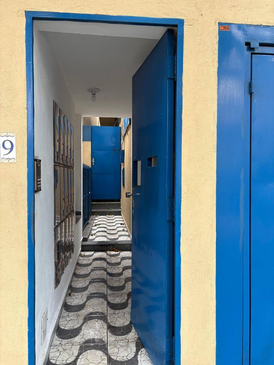 Interior de kitnet com corredor iluminado e acabamento moderno em São Paulo com porta de segurança